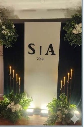 Custom monogram backdrop with greenery, tall candles and warm spot lighting